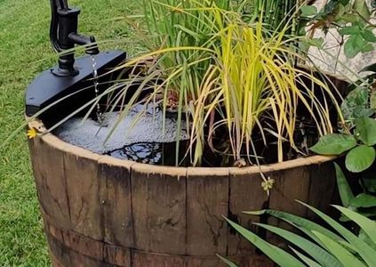 1/2 whisky barrel planter as a water feature with a antique style pump by wee dram Barrel creations