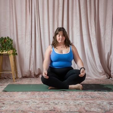 a woman sits in the lotus pose doing a yoga flow inside the blooming mystics yoga studio