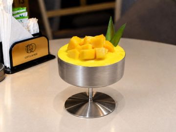 A mango dessert served in a metal bowl with fresh mango cubes.