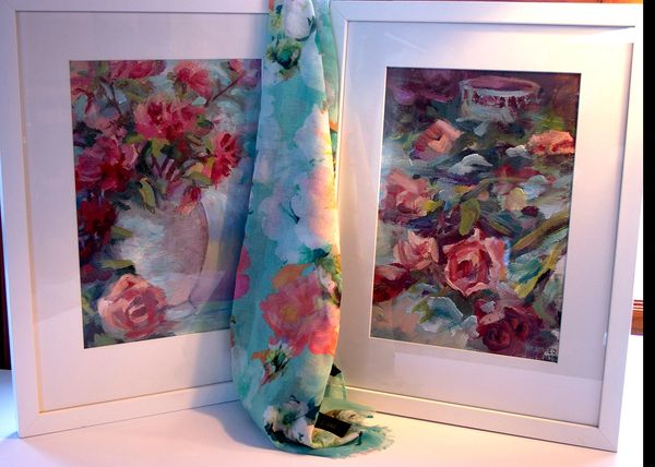 Two framed floral paintings with a matching floral scarf draped between them.