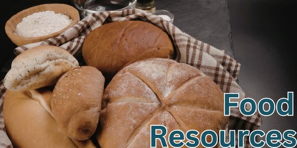 Assorted fresh bread loaves with flour and cloth on a dark surface.