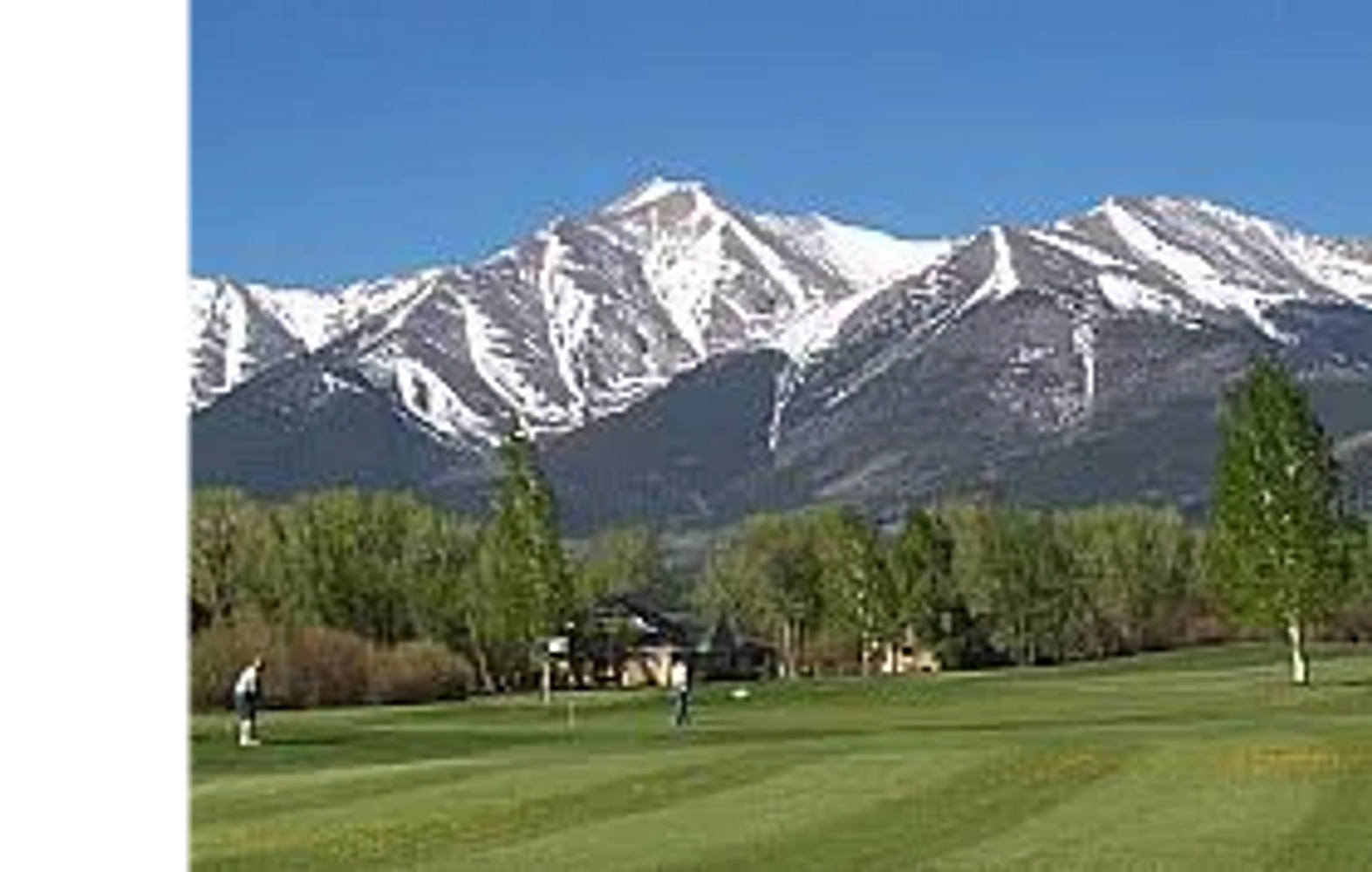 Golfers play on a lush course with snow-capped mountains in the background.