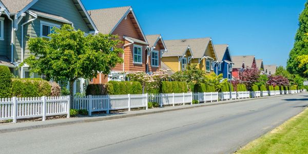 Suburban residential street with visible public sidewalk and colorful houses, showing accessible and