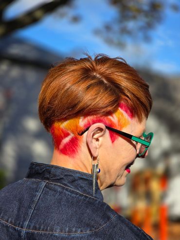 Woman with colorful undercut hairstyle and green glasses.