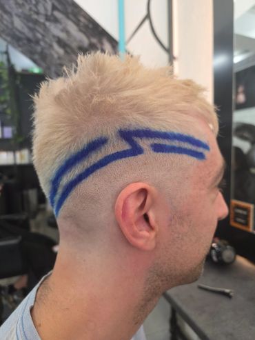 Blonde hair with blue artistic lines shaved on the side.