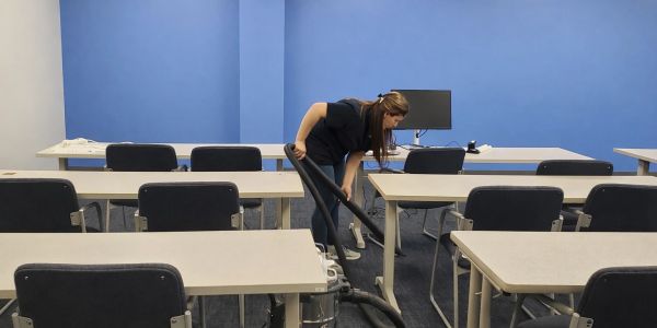 A woman vacuuming an empty classroom.