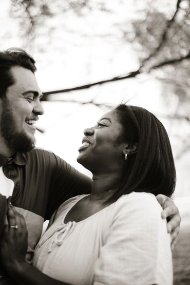 A joyful couple sharing a tender moment outdoors, smiling warmly at each other.