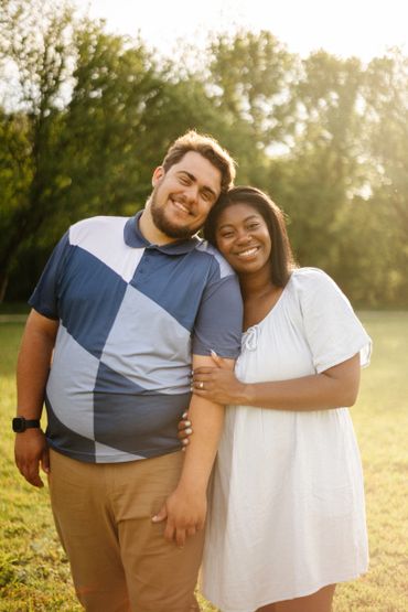 Happy couple embracing outdoors in sunny park.