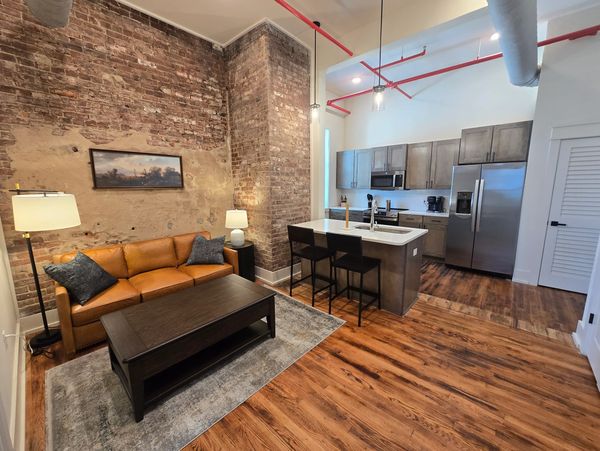 Cozy living room with exposed brick walls and modern kitchen.