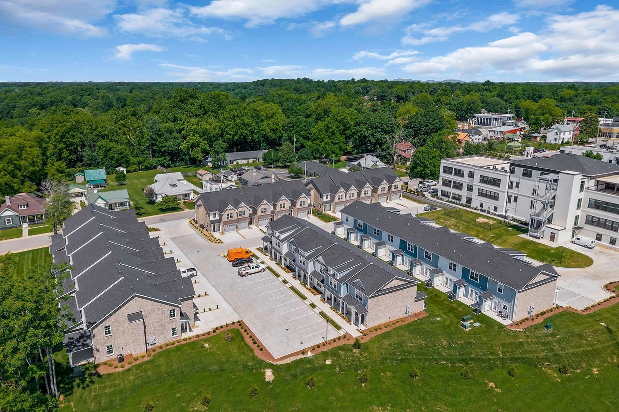 Aerial view of a modern townhouse community with parking and greenery.