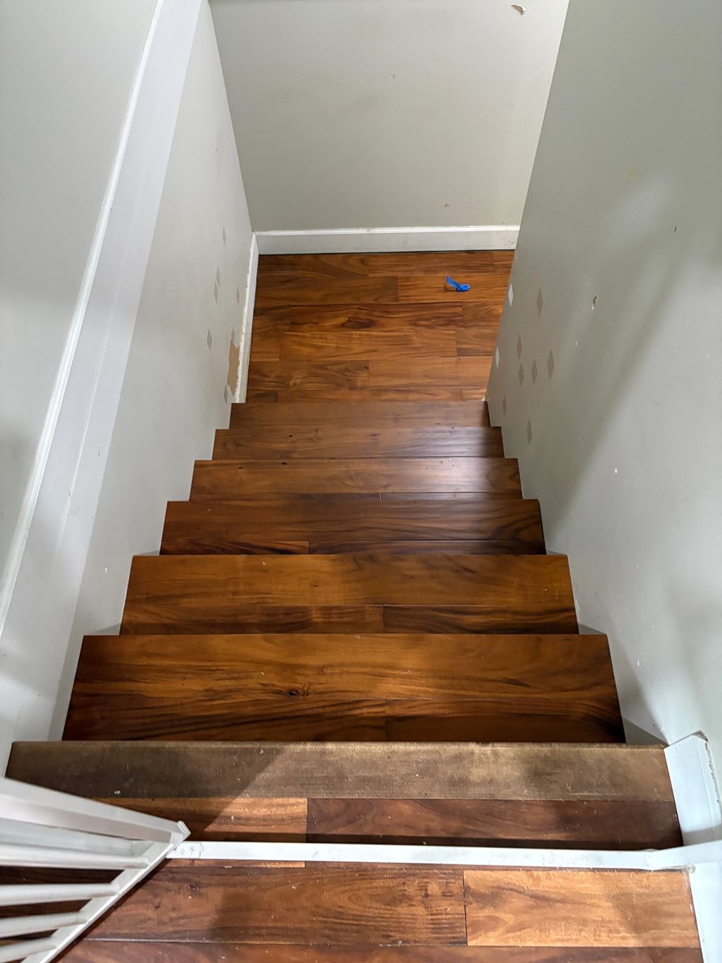 Wooden stairs descending to a lower floor with a blue balloon piece on the floor.
