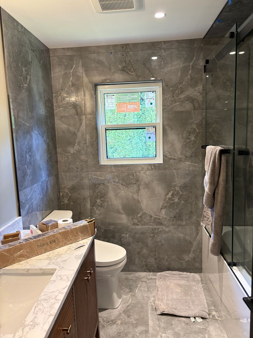 Modern bathroom with gray marble tiles and wooden vanity.