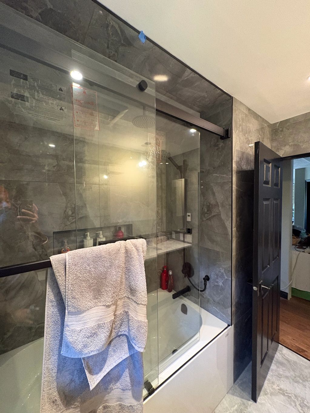 Modern bathroom with glass shower doors and gray marble walls.