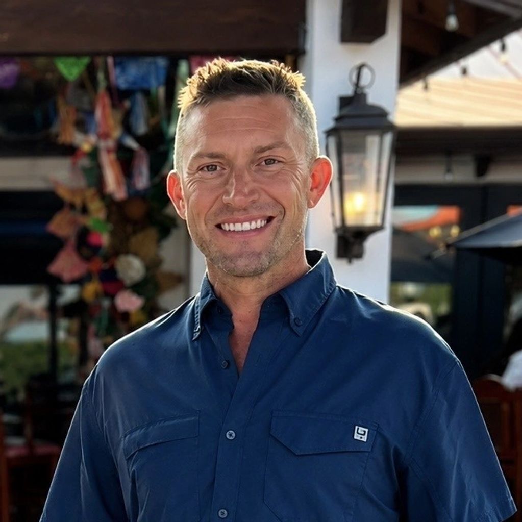 Smiling man in a blue shirt with short blond hair.