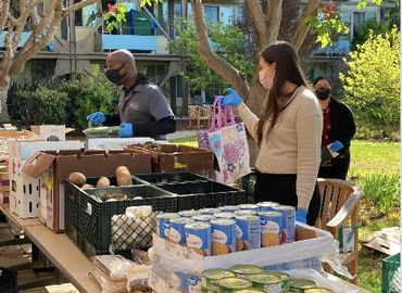 Volunteers distributing food outdoors while wearing masks and gloves.