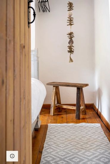 Rustic wooden stool in a cozy, minimalist bedroom corner.