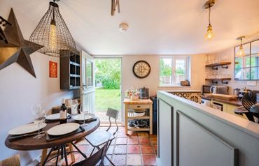 Cozy kitchen and dining area with rustic decor and open door to garden.