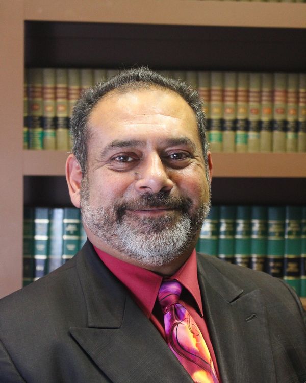 Smiling man in suit with bookshelves in background.