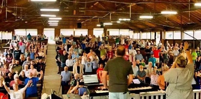 Large crowd attending an indoor event with speakers on stage.