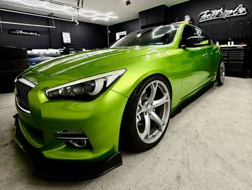 A shiny green sports car with sleek design in a garage.