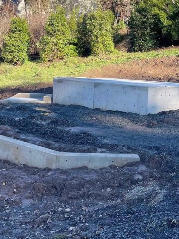 Freshly poured concrete steps and retaining walls in a garden under construction.