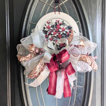 Decorative floral wreath with ribbons on a door.