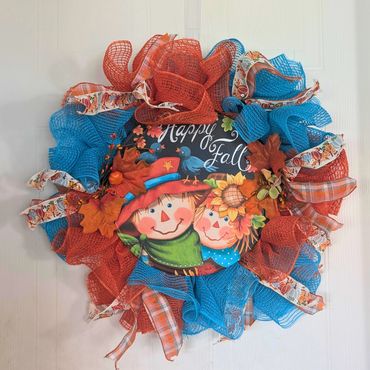 Colorful fall wreath with scarecrow faces and ribbons.