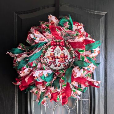 Festive Christmas wreath with gingerbread decorations and colorful ribbons.