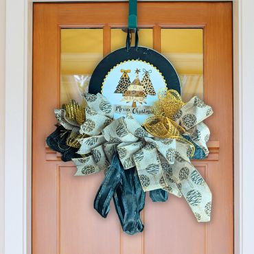Christmas wreath with ribbons and a festive sign on a door.