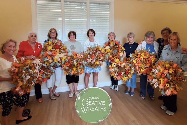 Group of women holding colorful autumn wreaths.