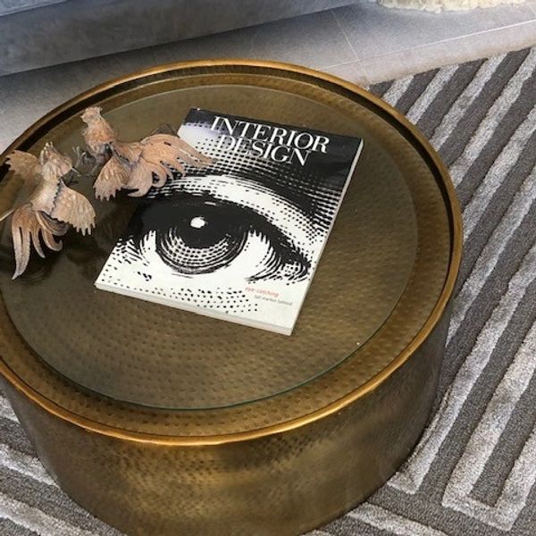 Hammered brass , glass top coffee table , brass decor (fighting cocks) on a wool geometric area rug.