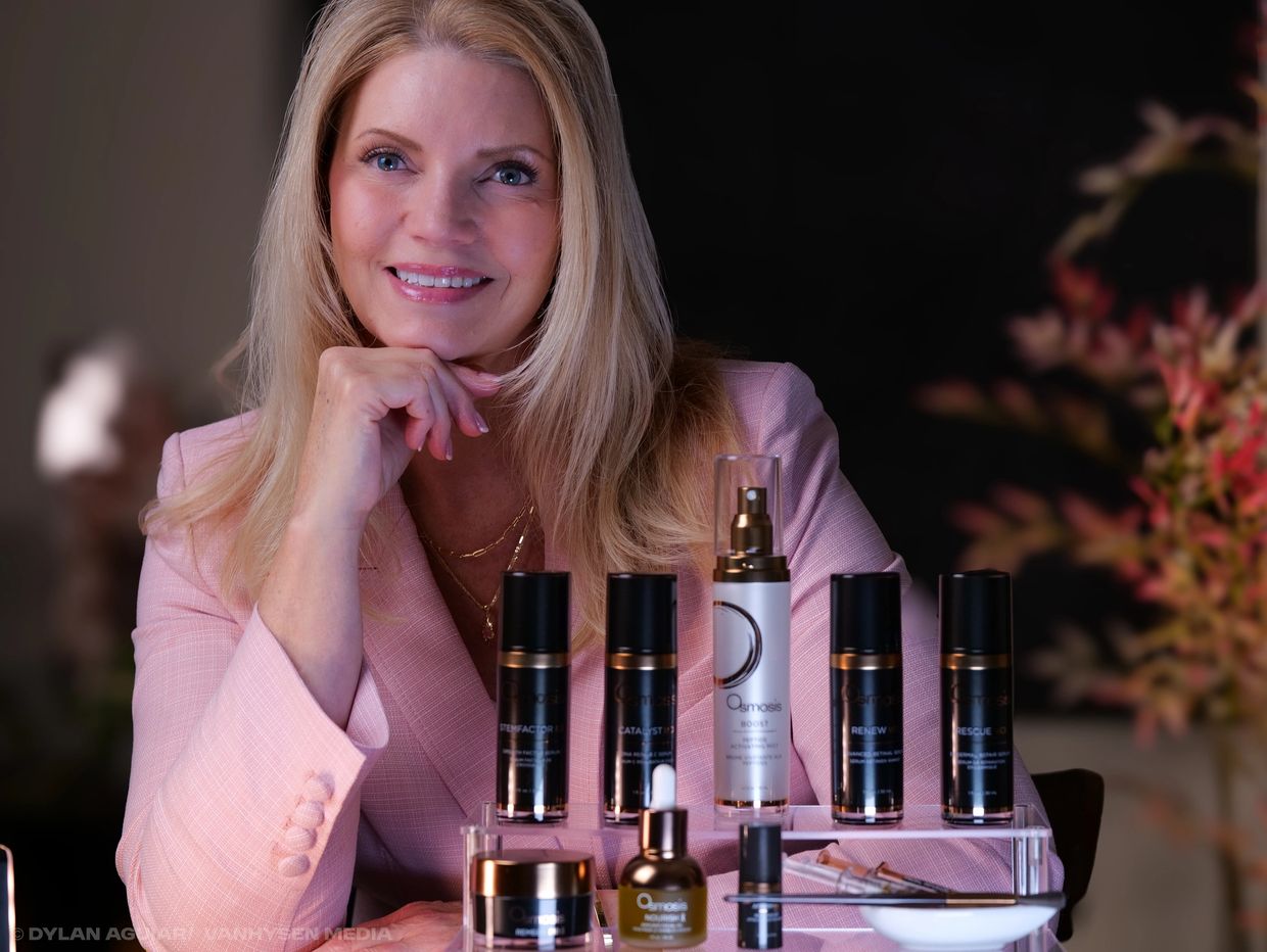 Woman in pink blazer with skincare products.