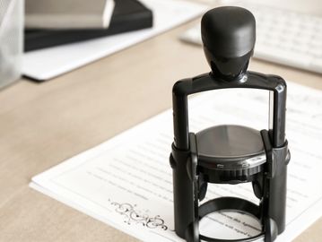 A black self-inking stamp on a document on a desk.