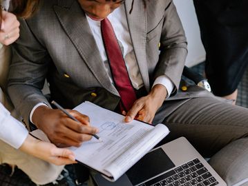 Businessman in a suit reviewing and signing documents with colleagues.