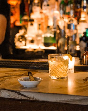 A smoky cigar and a drink on a bar counter.