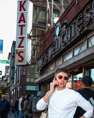 Young man talking on phone outside Katz's Delicatessen.