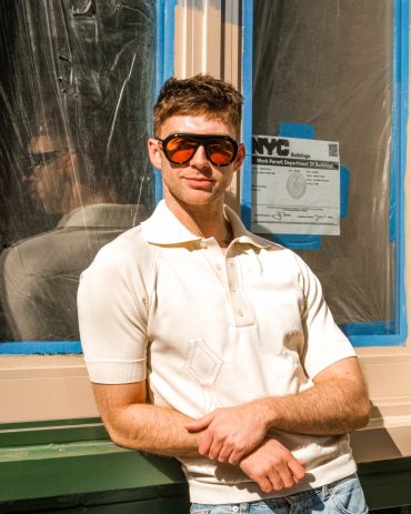 Man wearing oversized orange sunglasses and a white shirt.