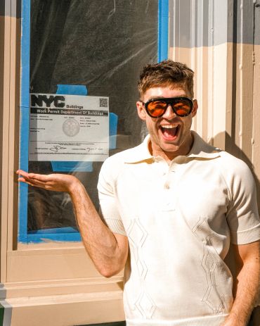 Man excitedly posing next to NYC work permit.
