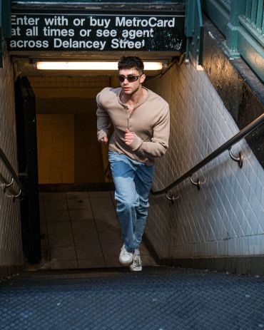 Man running up subway stairs with sunglasses.