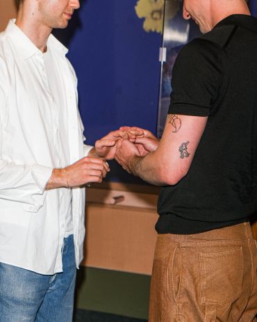 Two people holding hands indoors.