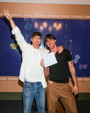 Two men celebrating with a certificate.