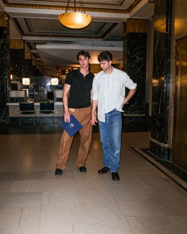 Two men standing in a marble-floored hallway.