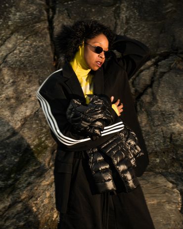 Woman wearing black coat with fur hood and sunglasses.