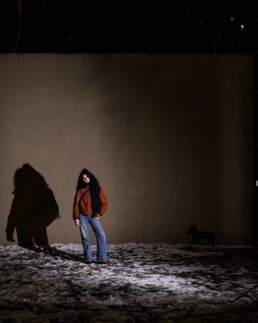 Person standing on snow with a large shadow at night.