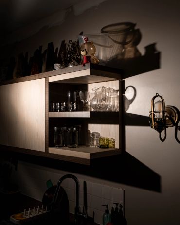 Shadow casting of glassware and a figurine in a dimly lit kitchen.