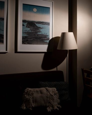 Cozy dimly lit corner with framed art and a floor lamp.