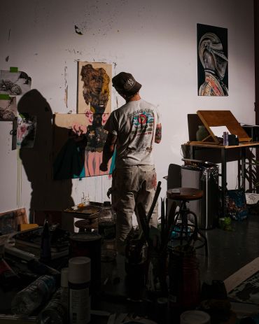 Artist painting in dim studio light.
