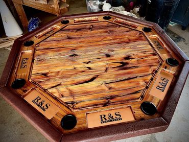 Octagonal wooden game table with cup holders and leather edges.