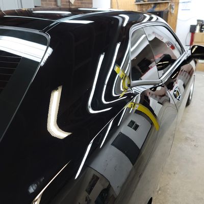 Close-up of a sleek black car with reflective surface in a garage.