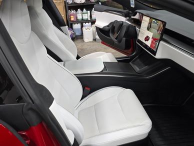 White leather seats inside a modern car with a touchscreen dashboard.